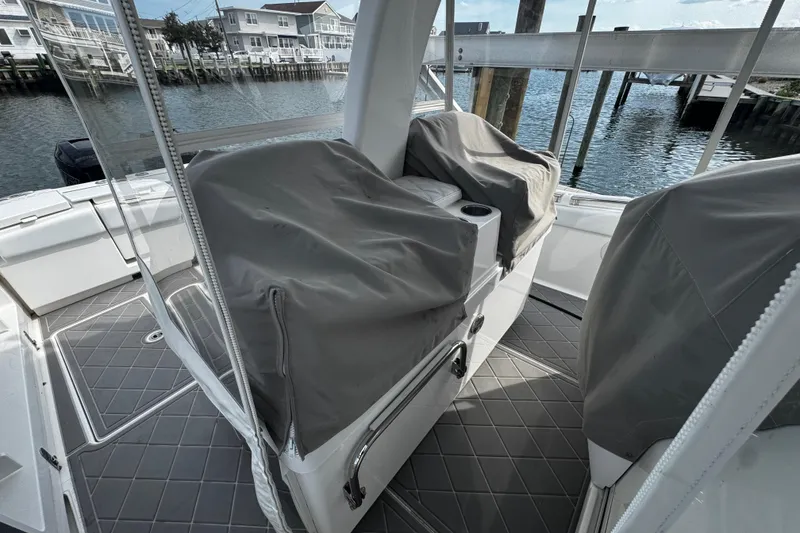 Slide: The Image of 2015 Belzona 32 CC boat interior with covered seating, docked by waterfront homes. - 40