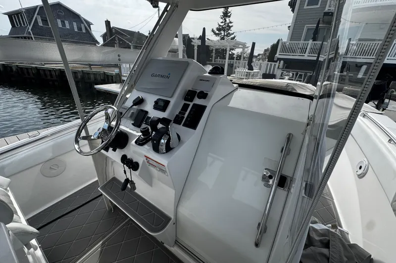 Slide: The Image of 2015 Belzona 32 CC boat cockpit with Garmin navigation system, docked near waterfront homes. - 42