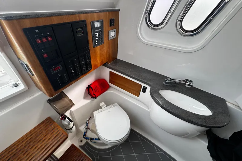 Slide: The Image of Interior of 2015 Belzona 32 CC boat featuring a compact bathroom with sink and control panel. - 49