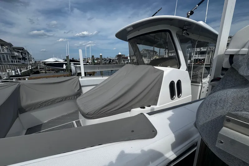 Slide: The Image of 2015 Belzona 32 CC boat docked at marina, featuring covered seating and clear skies. - 6