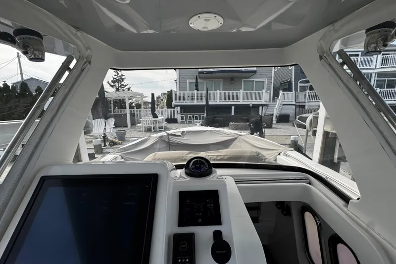 Slide: The Image of Cockpit view of a 2015 Belzona 32 CC boat docked near waterfront homes. - 68