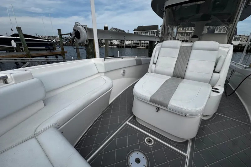 Slide: The Image of 2015 Belzona 32 CC boat interior with cushioned seating and sleek design at a marina. - 77