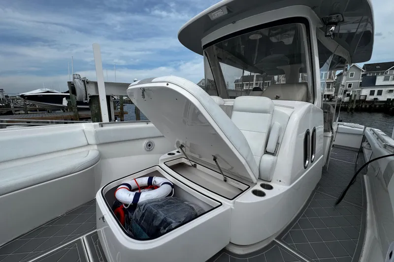 Slide: The Image of 2015 Belzona 32 CC boat with open storage compartment, docked near waterfront homes. - 83