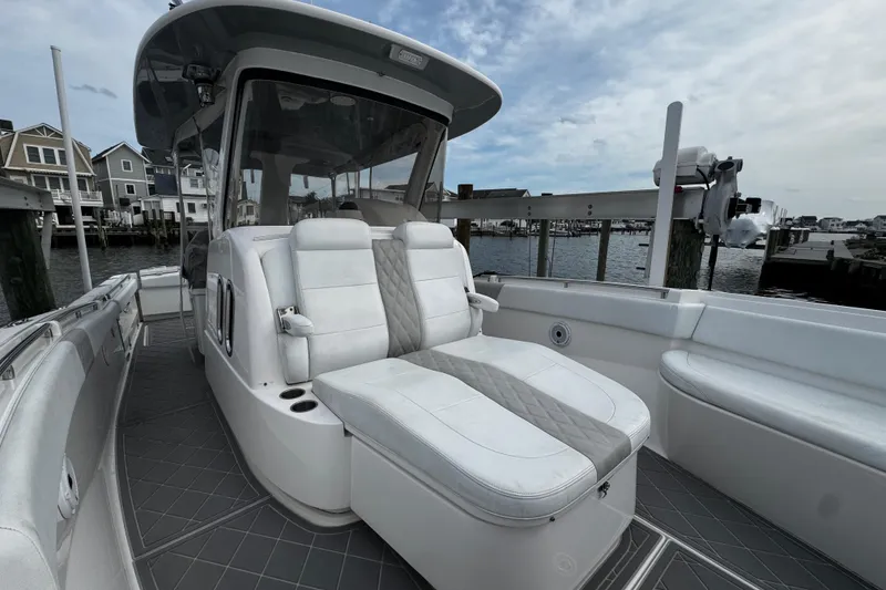 Slide: The Image of 2015 Belzona 32 CC boat interior with white seating, docked near waterfront homes. - 87