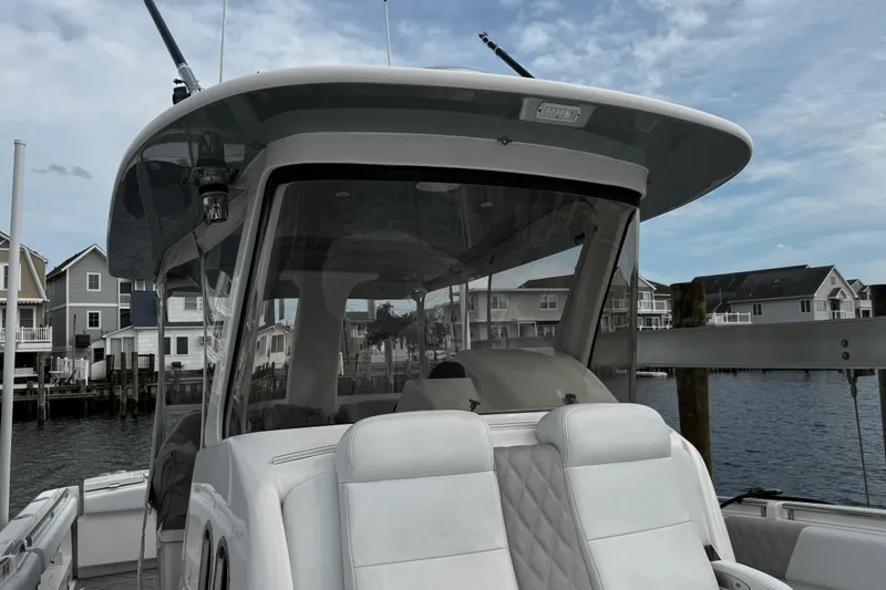 Slide: The Image of 2015 Belzona 32 CC boat docked near waterfront homes under a cloudy sky. - 88