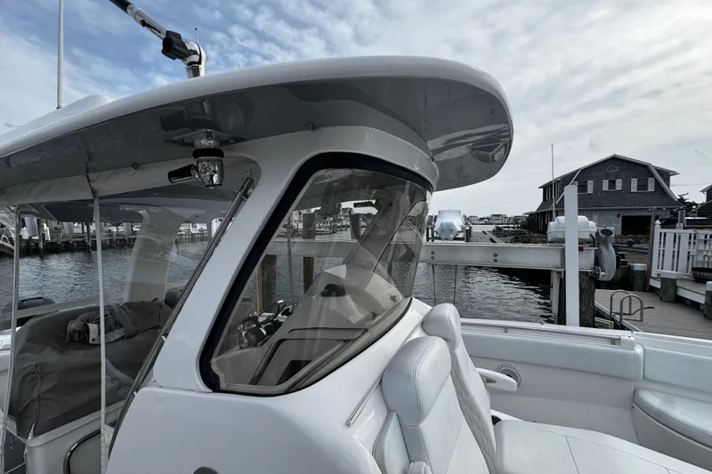Slide: The Image of 2015 Belzona 32 CC boat docked at marina, showcasing helm and seating area. - 90