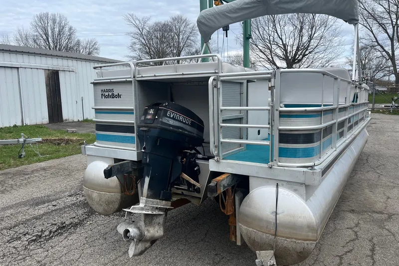 Slide: The Image of 1992 Harris FloteBote 240 Classic pontoon boat with Evinrude outboard motor, parked outdoors. - 5