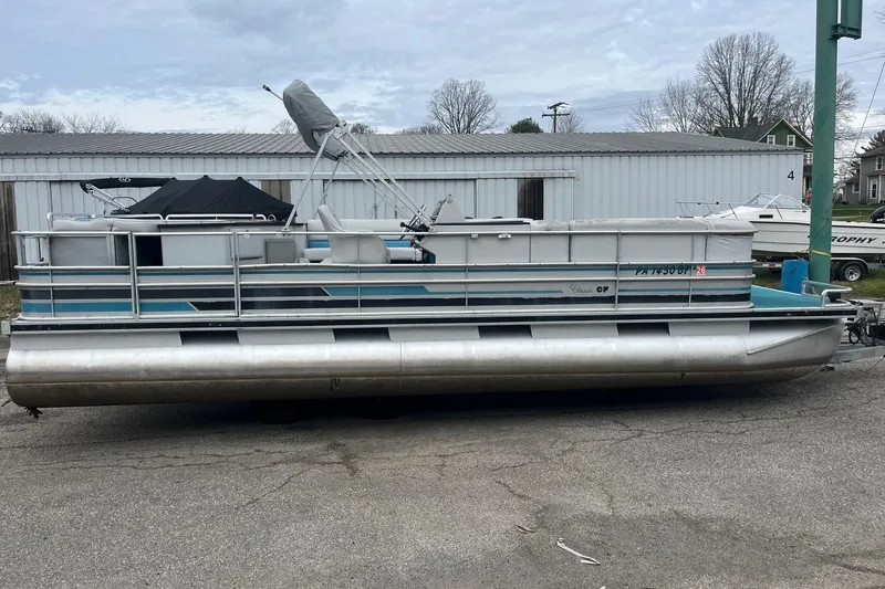 Slide: The Image of 1992 Harris FloteBote 240 Classic pontoon boat parked on pavement, featuring a sleek design. - 6