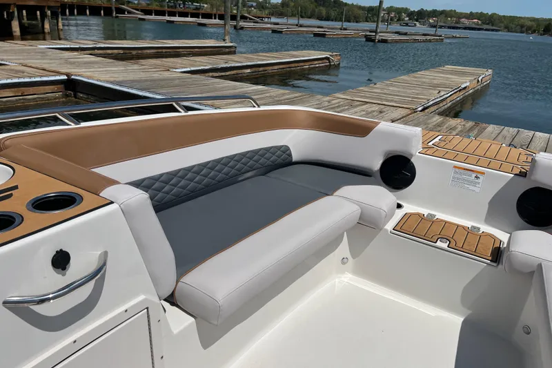 Slide: The Image of 2026 Starcraft SVX 211 OB boat interior with cushioned seating and cup holders at a dock. - 10