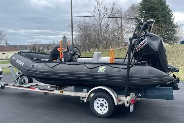The Image of 1997 Zodiac inflatable boat on trailer with Mercury outboard motor, parked outdoors. - 1