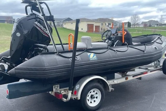 Slide: The Image of 1997 Zodiac inflatable boat on trailer with Mercury outboard motor, parked in residential area. - 3