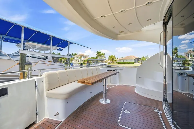 Slide: The Image of Luxurious 2006 Marquis 59 yacht deck with seating, wooden table, and marina view. - 31