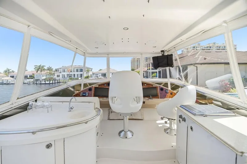 Slide: The Image of Interior view of a 2006 Marquis 59 yacht helm with modern seating and waterfront backdrop. - 41