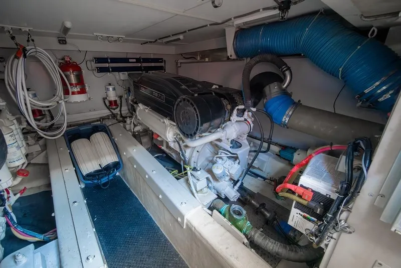 Slide: The Image of Engine room of a 2006 Marquis 59 yacht, featuring a diesel engine and fire safety equipment. - 48