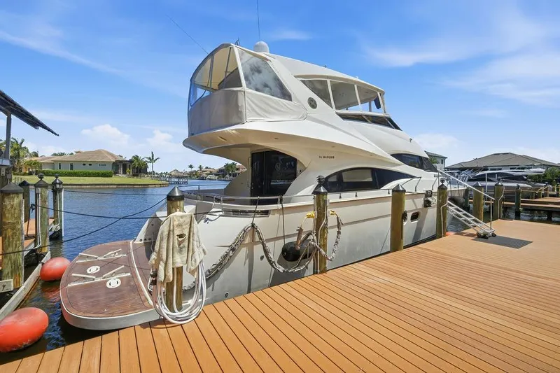 Slide: The Image of Luxury 2006 Marquis 59 yacht docked at a scenic marina under a clear blue sky. - 7