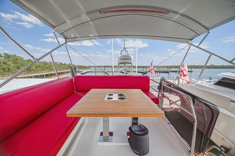 Slide: The Image of 2024 Prestige 520 yacht deck with red seating, wooden table, and canopy. - 11