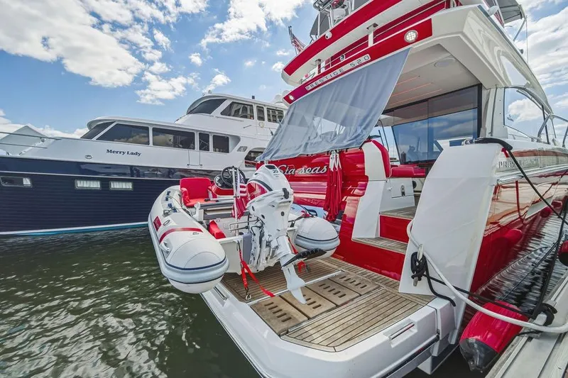 Slide: The Image of 2024 Prestige 520 yacht with inflatable boat, docked alongside another vessel under a blue sky. - 15