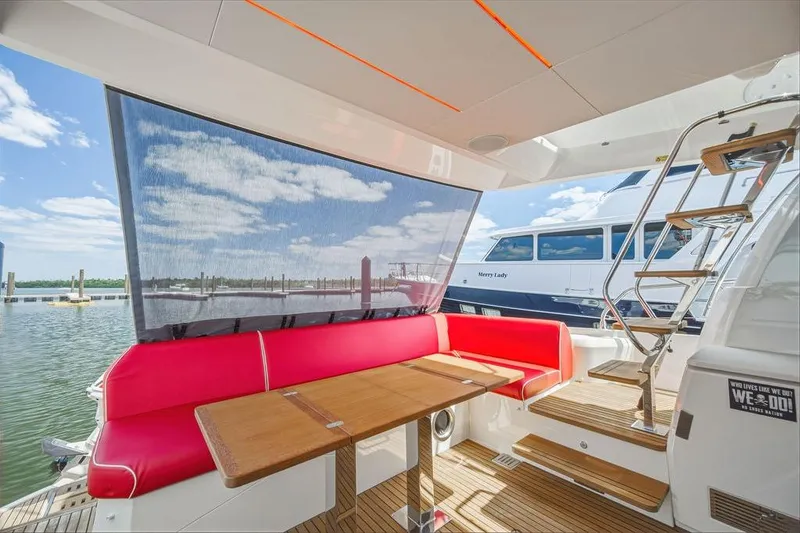 Slide: The Image of Luxurious 2024 Prestige 520 yacht interior with red seating, wooden table, and marina view. - 19