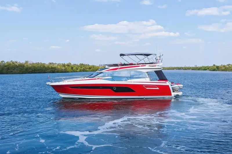 The Image of Red 2024 Prestige 520 yacht cruising on a serene blue lake under a clear sky. - 5
