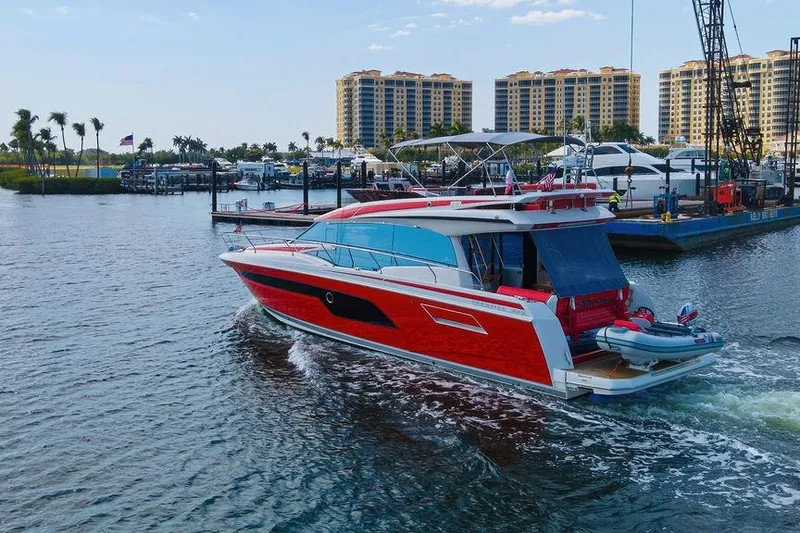 Slide: The Image of 2024 Prestige 520 yacht cruising in a marina with modern buildings in the background. - 8