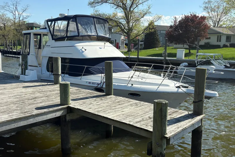 The Image of 2002 Carver 356 Aft Cabin Motor Yacht docked by a wooden pier on a sunny day. - 1