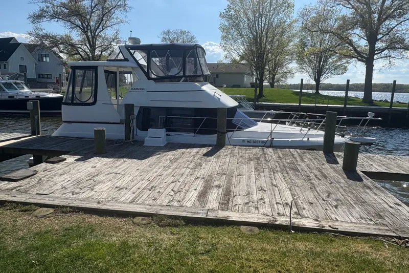 Slide: The Image of 2002 Carver 356 Aft Cabin Motor Yacht docked by a wooden pier, surrounded by trees. - 4