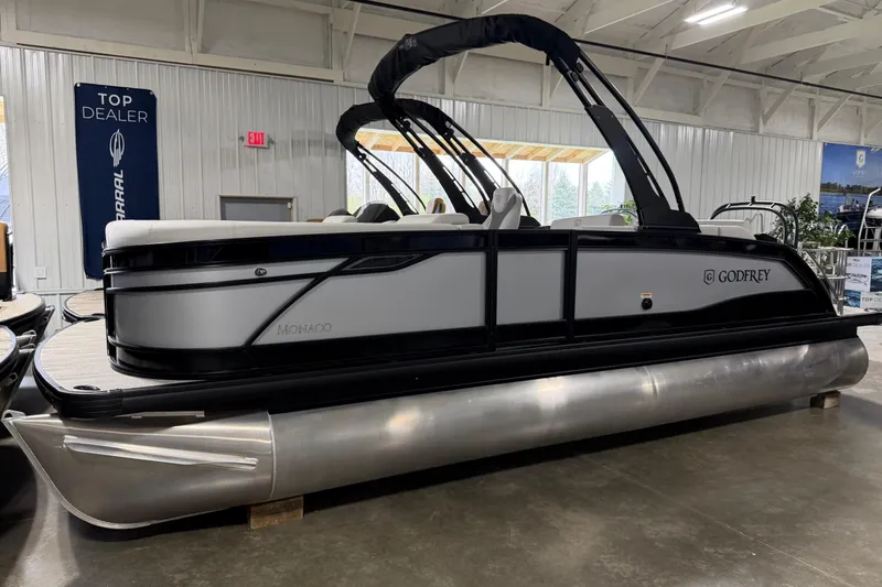 The Image of 2026 Godfrey Monaco 235 SFL pontoon boat displayed indoors at a dealership. - 1