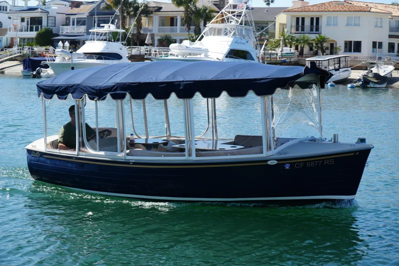 The Image of 2008 Duffy Snug Harbor 18 electric boat cruising in a marina with waterfront homes. - 1