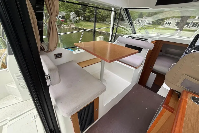 Slide: The Image of Interior of 2017 Jeanneau NC 895 boat with seating and table, docked by lakeside homes. - 8