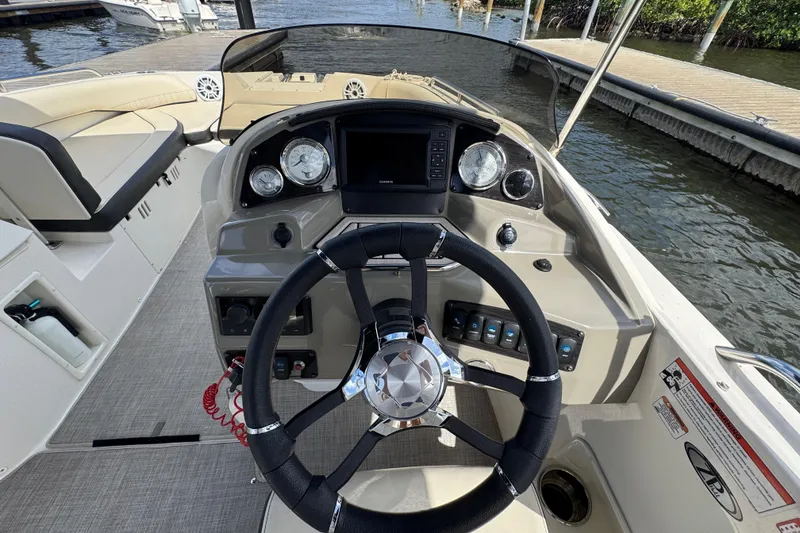 Slide: The Image of 2022 Stingray 192 SC boat dashboard with steering wheel and gauges, docked by the water. - 11