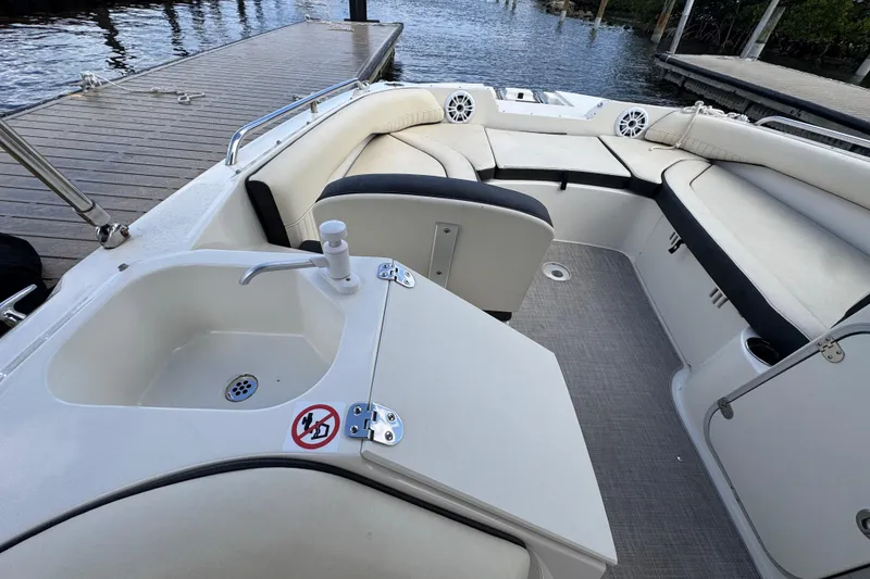 Slide: The Image of 2022 Stingray 192 SC boat interior with seating and sink, docked by the water. - 16