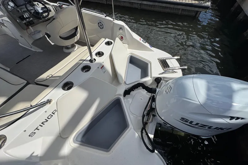 Slide: The Image of 2022 Stingray 192 SC boat interior with Suzuki outboard motor, docked by water. - 2