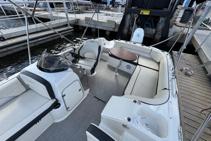 Slide: The Image of 2022 Stingray 192 SC boat interior with seating, table, and helm at a dock. - 22