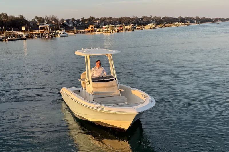 Slide: The Image of 2023 Boston Whaler 220 Dauntless boat cruising on calm waters near a dock. - 11