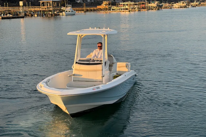 Slide: The Image of 2023 Boston Whaler 220 Dauntless boat cruising on calm waters near a dock. - 13