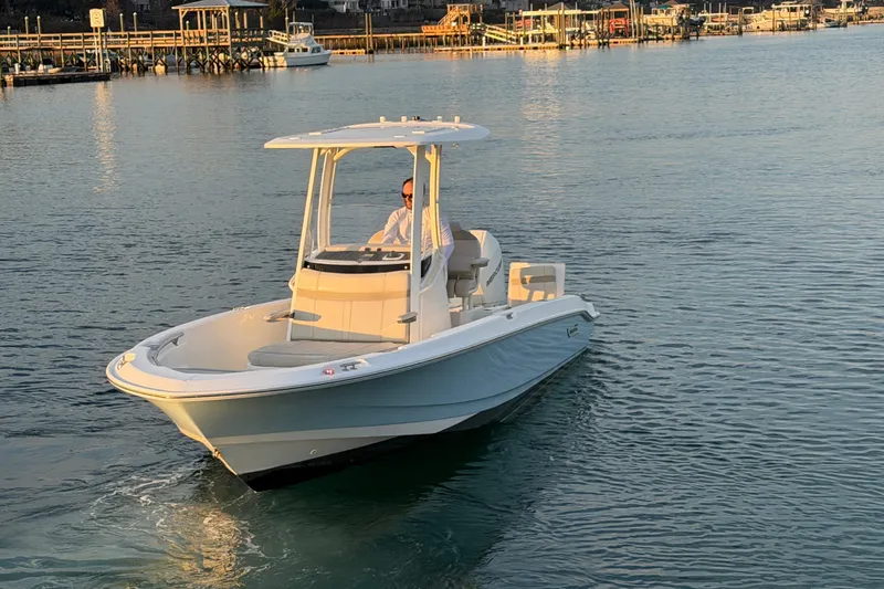 Slide: The Image of 2023 Boston Whaler 220 Dauntless boat cruising on calm waters near a dock. - 14