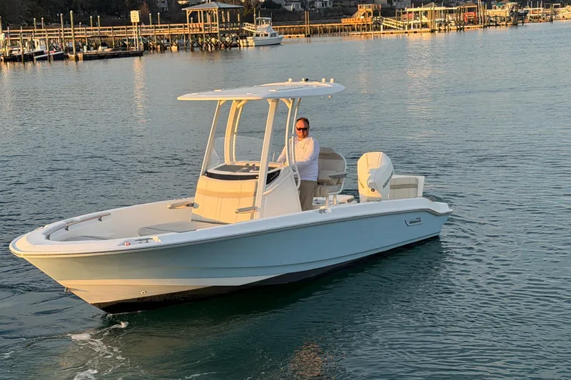 Slide: The Image of 2023 Boston Whaler 220 Dauntless boat cruising on calm waters near a dock. - 16