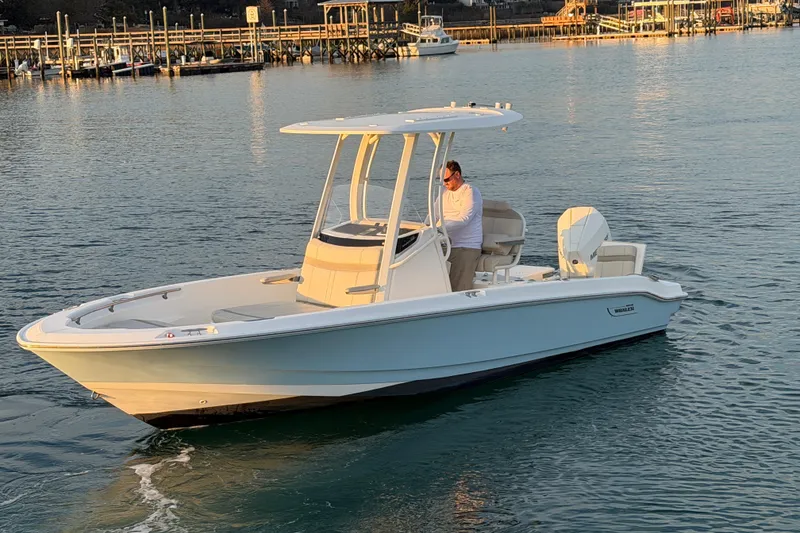 Slide: The Image of 2023 Boston Whaler 220 Dauntless boat cruising on calm waters near a dock. - 17