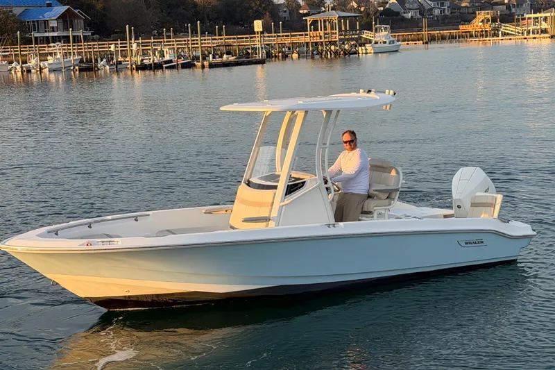 Slide: The Image of 2023 Boston Whaler 220 Dauntless boat on calm water near a dock. - 18