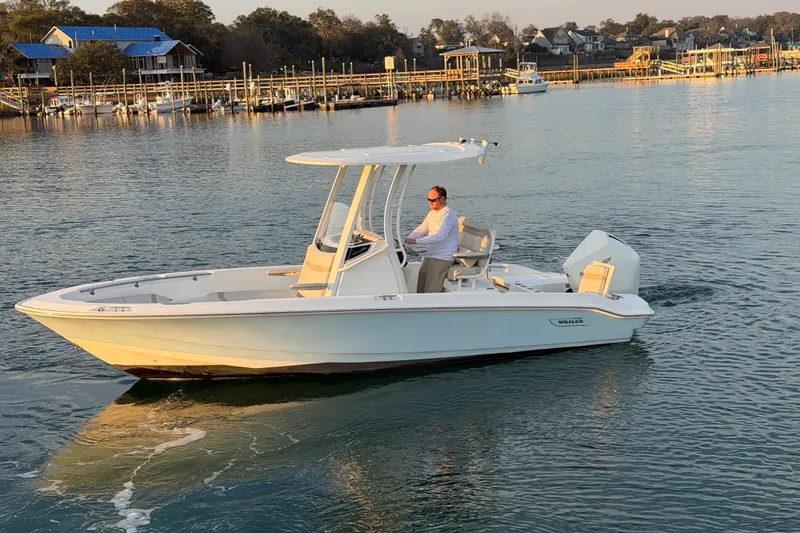 Slide: The Image of 2023 Boston Whaler 220 Dauntless boat cruising on calm waters near a marina. - 19