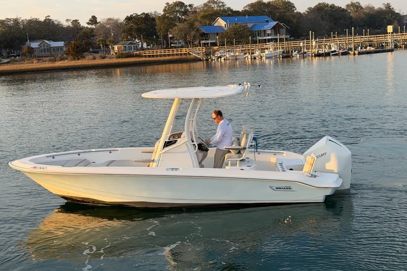 Slide: The Image of 2023 Boston Whaler 220 Dauntless boat cruising on calm water near a dock. - 21