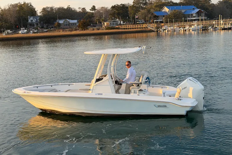 Slide: The Image of 2023 Boston Whaler 220 Dauntless boat cruising on calm water near a dock. - 22