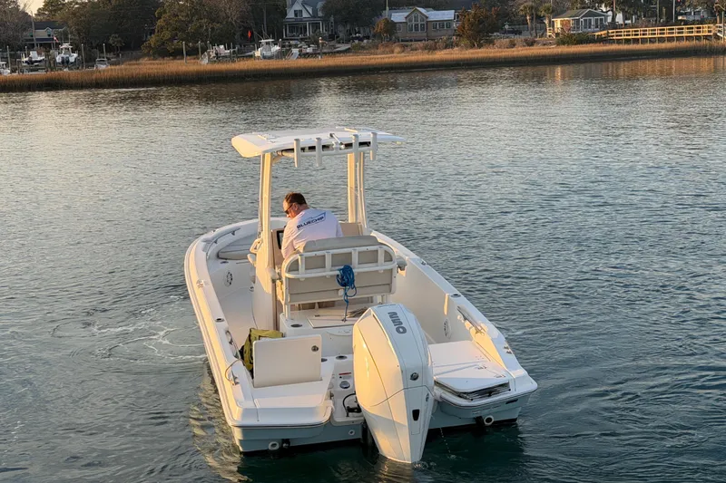 Slide: The Image of 2023 Boston Whaler 220 Dauntless boat cruising on calm waters near a shoreline. - 26