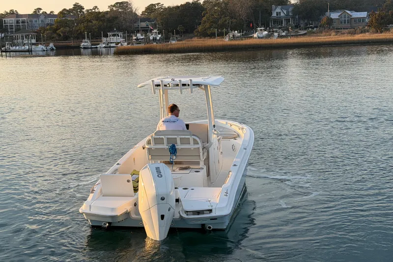 Slide: The Image of 2023 Boston Whaler 220 Dauntless boat cruising on calm water near a marina. - 29