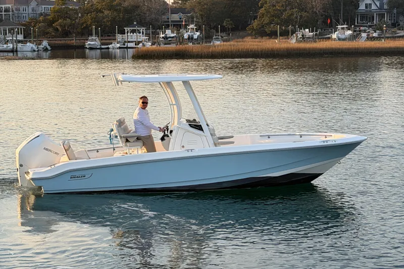 Slide: The Image of 2023 Boston Whaler 220 Dauntless boat cruising on calm waters near a marina. - 35