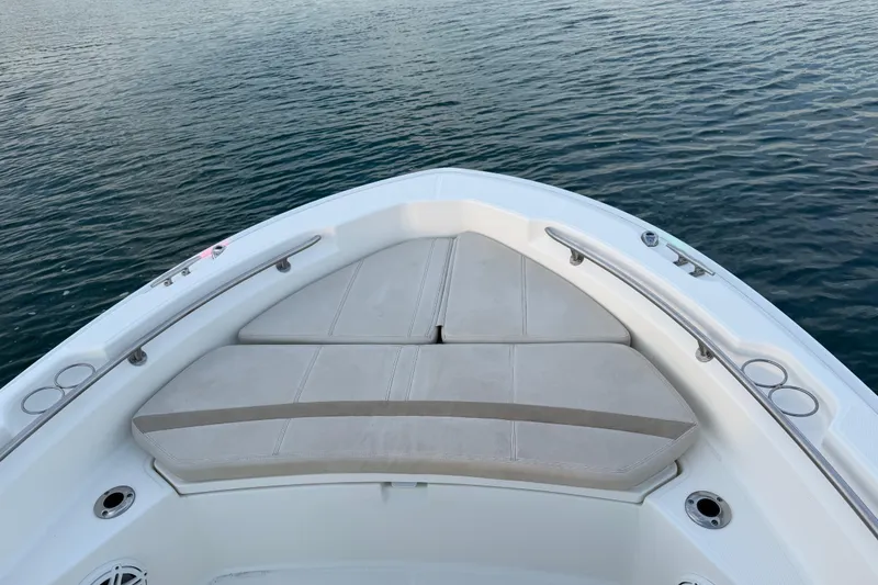 Slide: The Image of 2023 Boston Whaler 220 Dauntless boat bow with cushioned seating on calm water. - 36