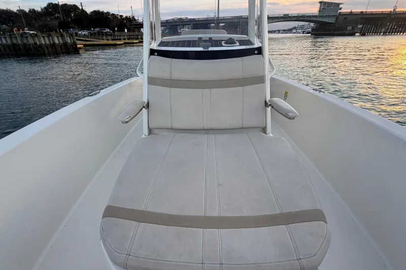 Slide: The Image of 2023 Boston Whaler 220 Dauntless boat interior with cushioned seating, dockside view at sunset. - 38
