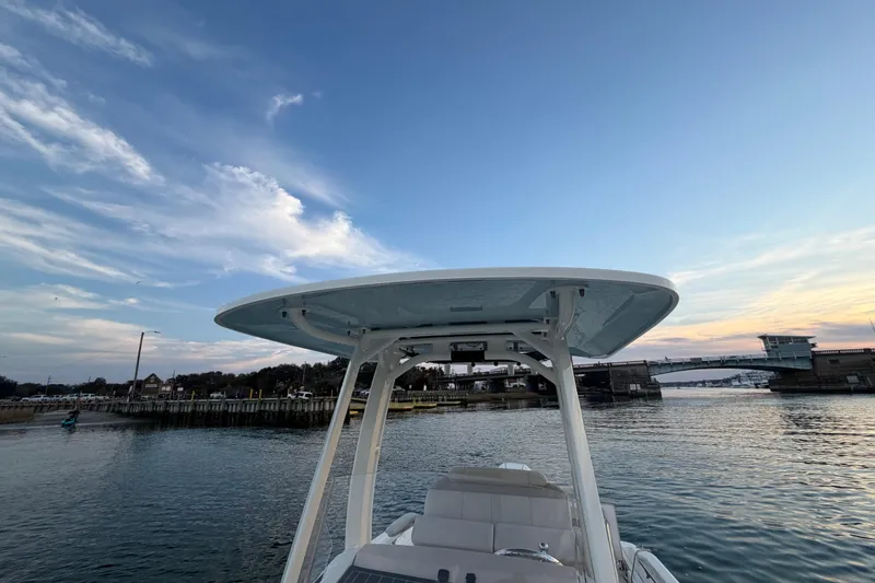 Slide: The Image of 2023 Boston Whaler 220 Dauntless boat on calm water at sunset near a bridge. - 40