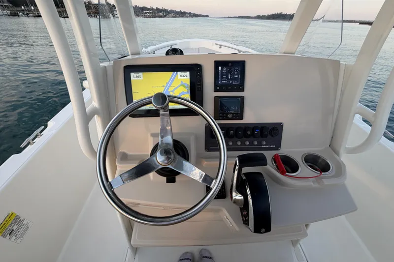 Slide: The Image of Boston Whaler 220 Dauntless 2023 helm with navigation display and controls on calm water. - 41