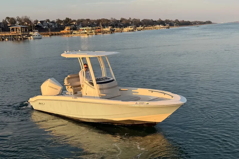 Slide: The Image of 2023 Boston Whaler 220 Dauntless boat cruising on calm waters near a coastal town. - 5